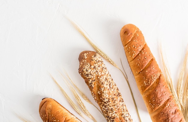 Baguette fresca croccante con vari semi utili su sfondo bianco con sfondo bianco vista dall'alto di cereali