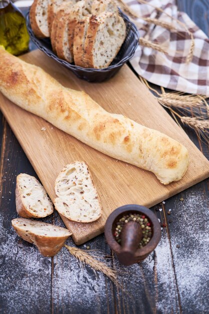 Baguette fresca e pane affettato sul tagliere di legno al tavolo della cucina