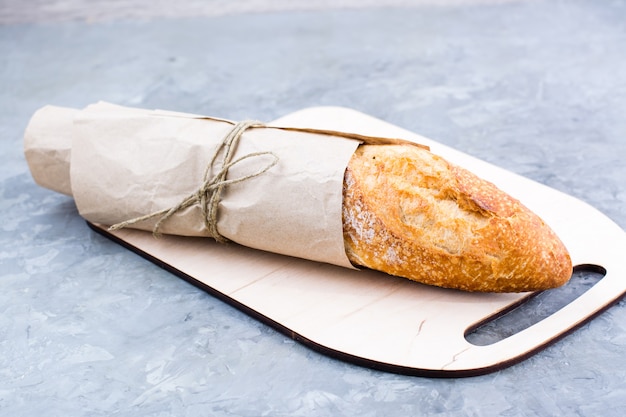 Baguette fresche in carta da imballaggio sul tagliere sul tavolo