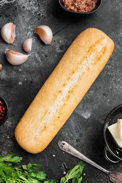 Baguette prezzemolo erbe burro ingredienti su tavola di pietra scura nera sfondo vista dall'alto piatto lay