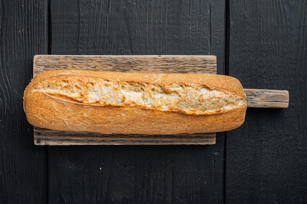 Baguette su tavola di legno nera sfondo vista dall'alto piatto laico