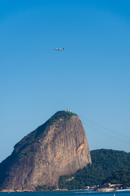 Baia di Guanabara a Rio de Janeiro in Brasile con Pan di Zucchero sullo sfondo Bellissimo paesaggio e collina con l'aereo del mare che passa sopra la cima della collina Giornata di sole