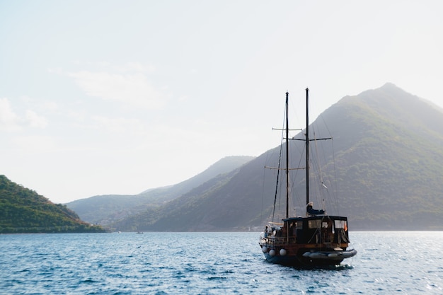 Baia di Kotor con uno yacht che galleggia sull'acqua sullo sfondo di montagne e cielo.