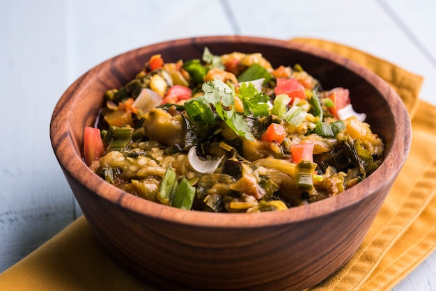 Baigan/Baingan Bharta - Purè di melanzane arrosto cotte con spezie e verdure. Servito con pane piatto di farina di Jowar noto come bhakar/bhakri. servito su sfondo colorato o in legno