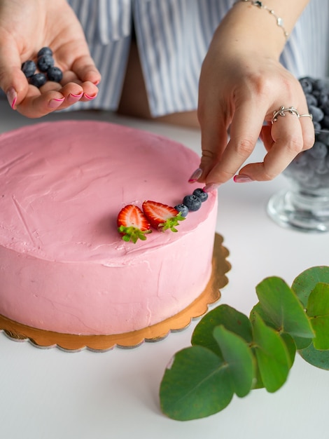 Baker aggiungendo mirtilli a una torta che decora