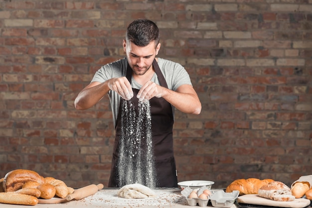 Baker che cade farina sopra l&#39;impasto in cucina