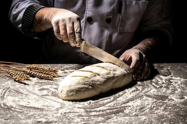 Baker che fa modelli sul pane crudo usando un coltello per modellare l'impasto prima della cottura