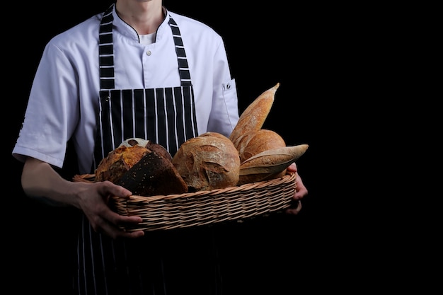 Baker detiene il cesto di pane isolato su sfondo nero