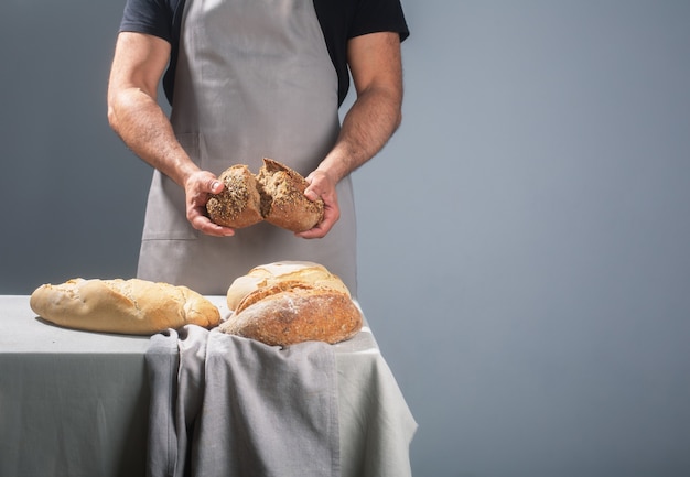 Baker holding pane appena sfornato sul tavolo su sfondo grigio