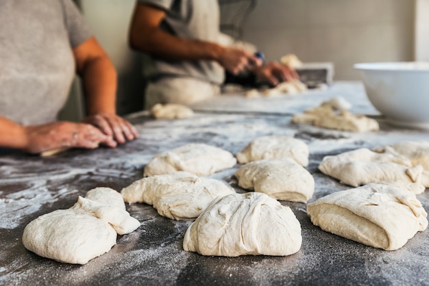 Baker preparare il pane. Primo piano delle mani che impastano la pasta. Concetto di panetteria.