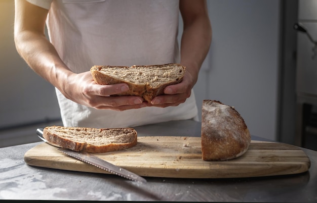 Baker taglia il pane appena sfornato con un coltello per verificarne la qualità Produzione di prodotti da forno come piccola impresa