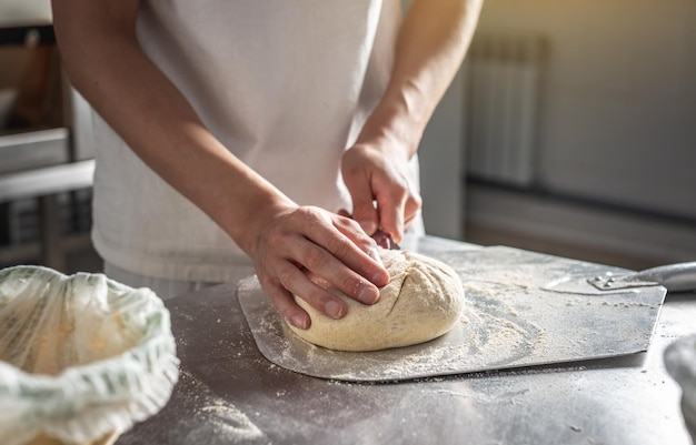 Baker taglia la pasta con un coltello prima di andare in forno per la cottura Produzione di prodotti da forno