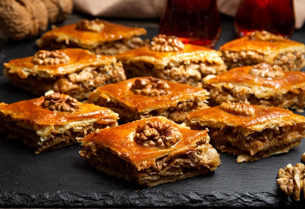 Baklava al miele con noci su ardesia nera Porzioni di dolci orientali Pezzi zuccherati turchi