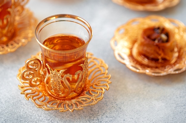 Baklava turco e tè turco in piatti orientali su sfondo grigio