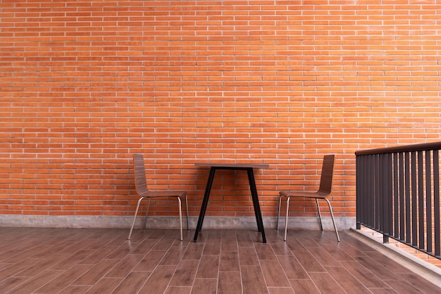 Balcone con muro di mattoni rossi e set di sedie da tavolo