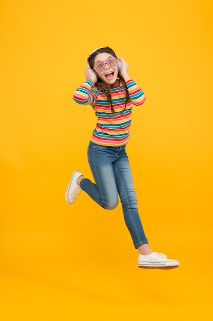 Balla e basta. il bambino salta con gli occhiali da festa. infanzia felice. solo divertendosi. la sua canzone preferita. l'adolescente ascolta musica in cuffia. bel ragazzo con i capelli intrecciati. glamour e divertente. vita moderna.