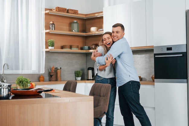 Ballando insieme Coppia che prepara il cibo a casa sulla cucina moderna