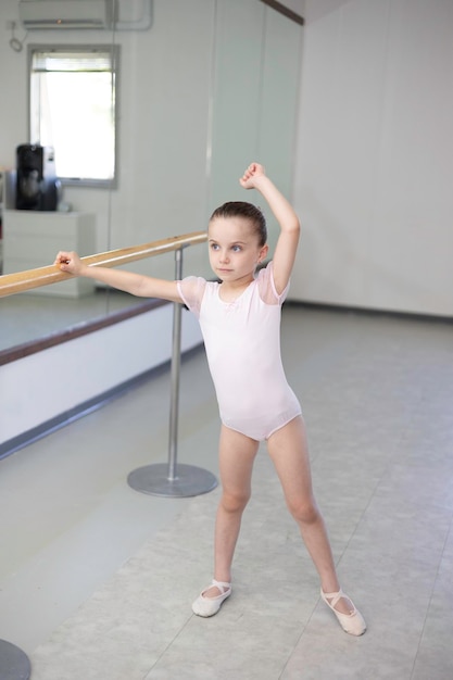 Ballerina del bambino della bambina sveglia in tutù rosa pallido e scarpe di balletto che praticano le mosse di danza.