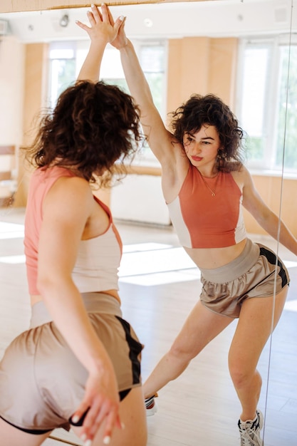 Ballerina di giovane donna che esegue una danza con riflesso speculare nello studio di danza