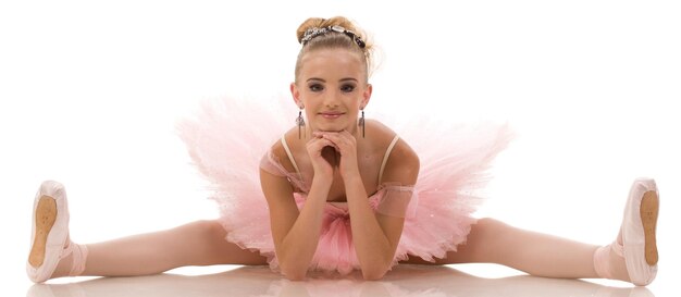 Ballerina di giovane donna in tutù bianco che balla sulle punte con le braccia sopra la testa in studio su uno sfondo scuro