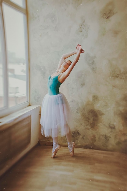 Ballerina giovane e aggraziata in scarpe da punta e un tutù balla in studio. Coreografia, danza