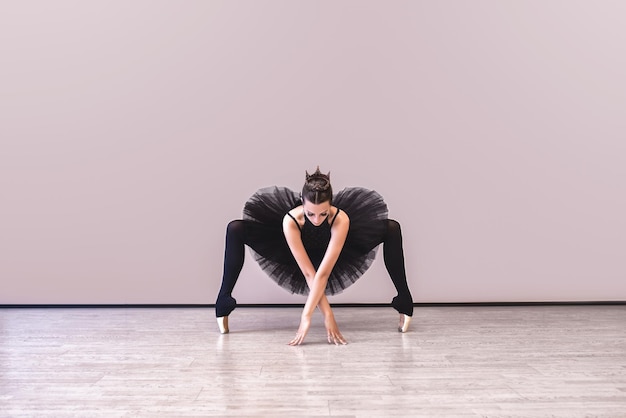 Ballerina in abito da cigno nero su sfondo wgite Giovane ballerina che si esercita prima della performance in tutù nero studio di danza classica spazio copia