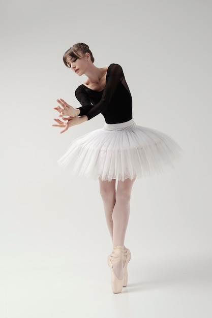 Ballerina in body nero e tutù posa in movimento mostrando elementi mentre si trova sulle punte