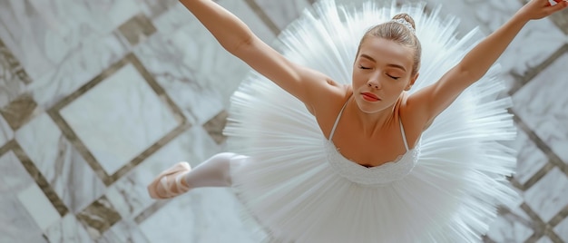 Ballerina professionista caucasica in tutu bianco e pointe posa con le mani alzate sopra la testa vista da una prospettiva alta sul pavimento in legno duro delle sale dello studio