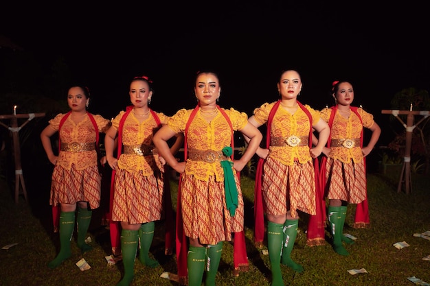 Ballerini balinesi in piedi insieme a sciarpa rossa e costumi arancioni sul palco dopo aver eseguito la danza tradizionale