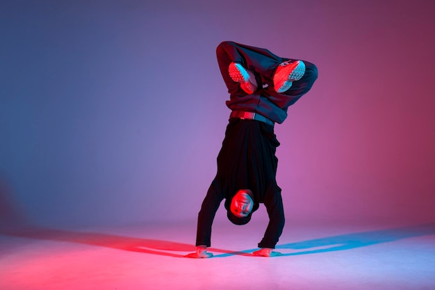 Ballerino che fa acrobazie e danza breakdance con luci al neon rosse e blu