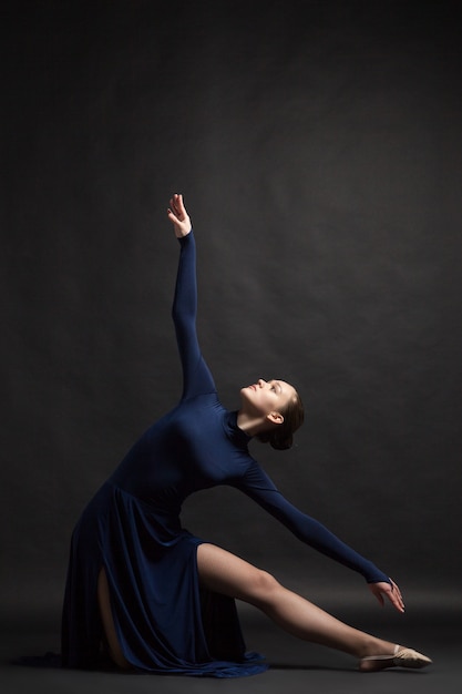 Ballerino in posa in abito lungo blu profondo su sfondo scuro