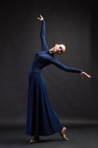 Ballerino in posa in abito lungo blu profondo su sfondo scuro