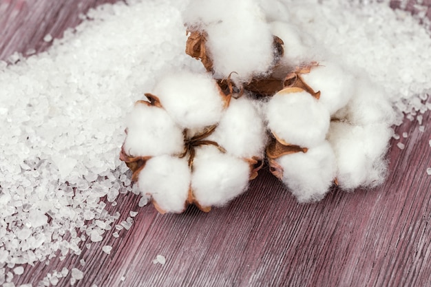 Ballflowers di cotone e sale marino bianco sul bordo di legno d'annata