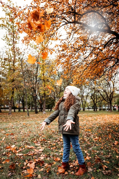 Bambina 5 anni divertendosi nella foresta di autunno