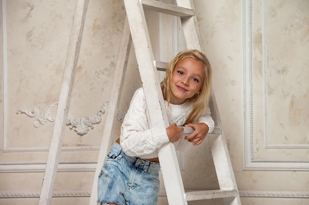 Bambina 67 anni modello principessa bionda in elegante vestire in posa alle scale che guarda l'obbiettivo nel soggiorno