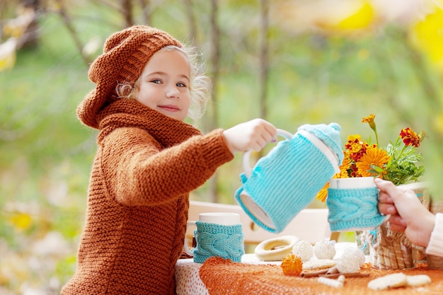 Bambina adorabile che beve tè nella sosta di autunno