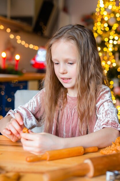 Bambina adorabile che cuoce i biscotti di pan di zenzero di Natale