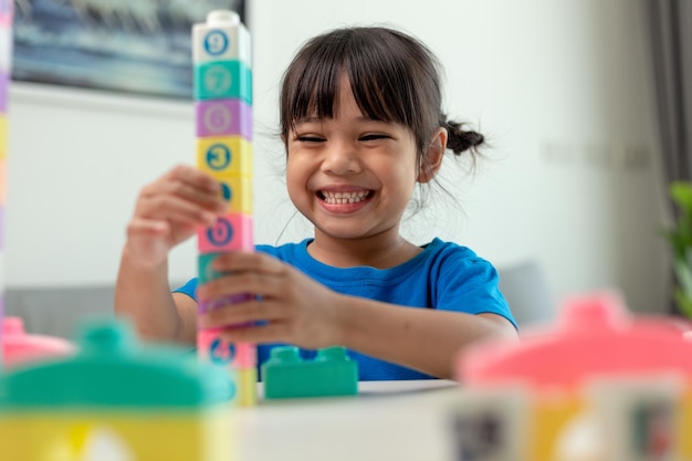 Bambina adorabile che gioca a blocchi giocattolo in una stanza luminosa