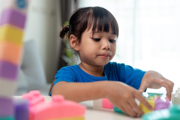 Bambina adorabile che gioca a blocchi giocattolo in una stanza luminosa