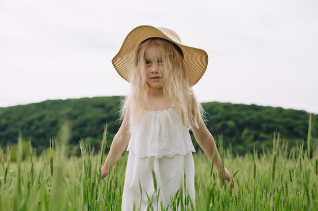 Bambina adorabile che gioca nel campo di grano in una calda giornata estiva