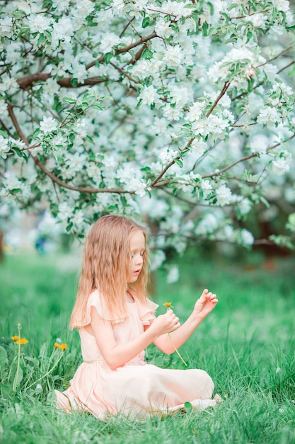 Bambina adorabile che gode del giorno di molla nel giardino di fioritura della mela