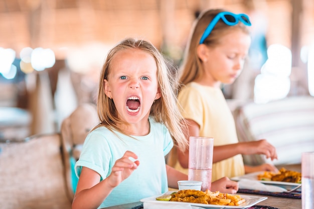 Bambina adorabile che mangia prima colazione al caffè all'aperto