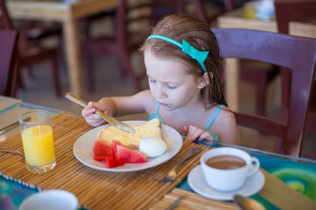 Bambina adorabile che mangia prima colazione al ristorante del ricorso