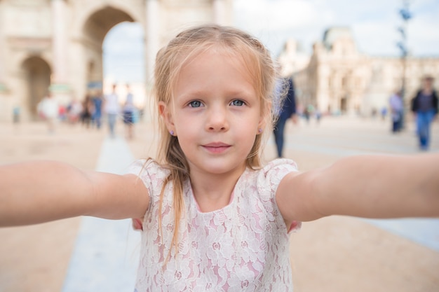 Bambina adorabile che prende selfie con il telefono cellulare all'aperto a Parigi