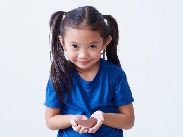 Bambina adorabile con cioccolato a forma di cuore isolato