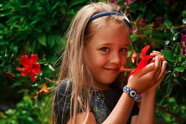 Bambina adorabile con fiore al bellissimo giardino