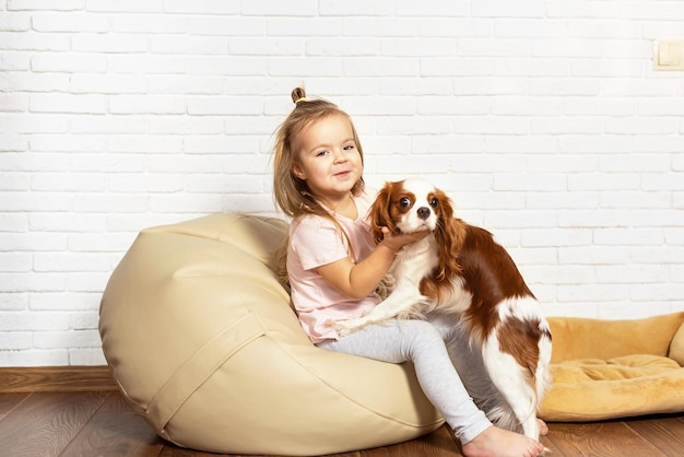 Bambina adorabile con il cucciolo che gioca a casa Bambino con cagnolino al coperto. L'animale domestico migliore e più amichevole per bambini e famiglie, amore per gli animali domestici, amore per i cani, rapporto speciale con l'animale domestico