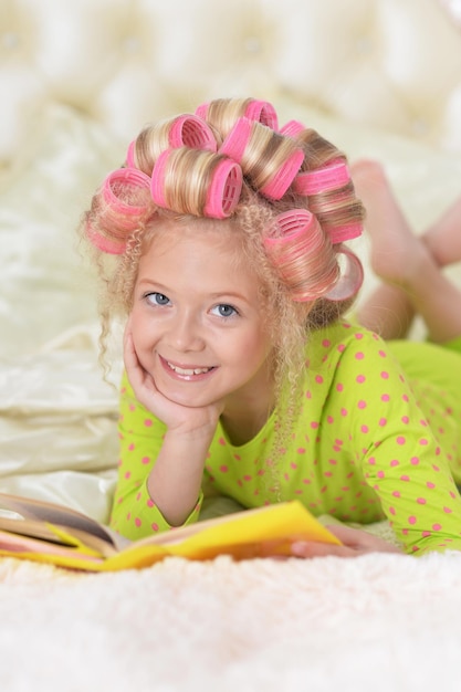 Bambina adorabile con la lettura rosa dei bigodini