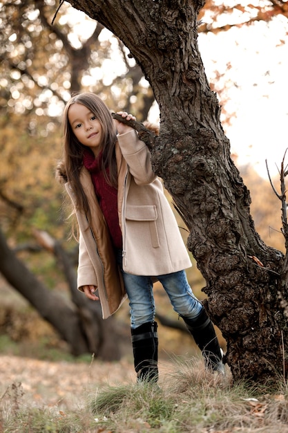 Bambina adorabile felice che gioca con le foglie cadute autunnali