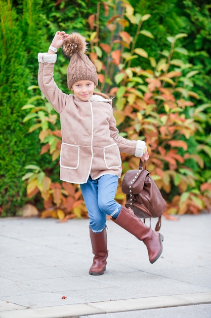 Bambina adorabile felice divertendosi all'aperto al bello giorno di autunno